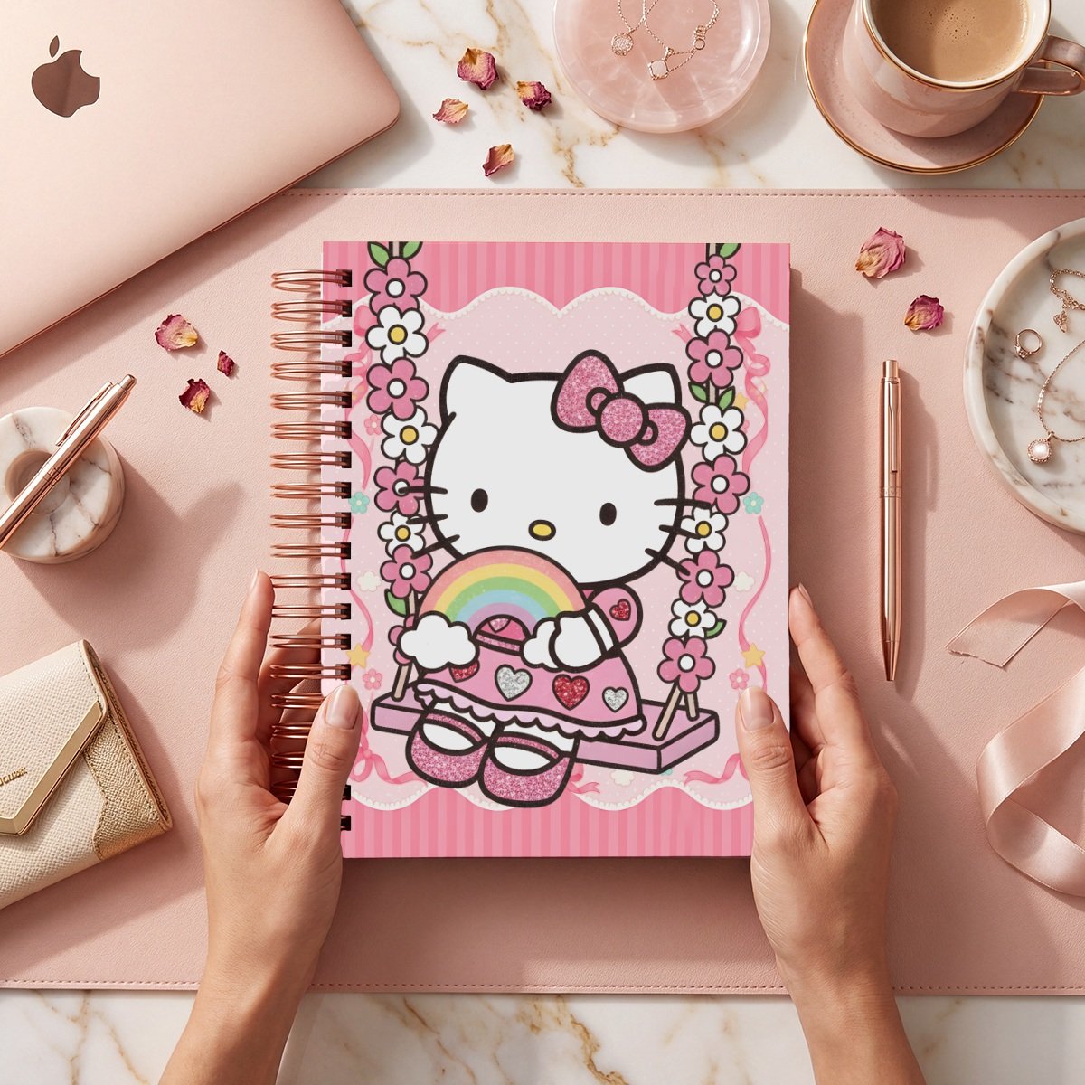 Mockup de portada Kitty 013: Kitty sentada en columpio de flores con arcoíris, fondo rosa de rayas y moños; frente del cuaderno sostenido por manos.